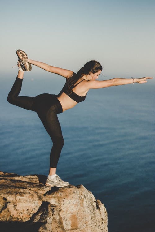 woman doing yoga on a rock near the sea